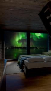 ein Schlafzimmer mit einem Bett mit Blick auf die Nordlichter in der Unterkunft Arctic Guesthouse & Igloos in Ranua
