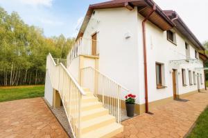 a white building with stairs and a potted plant at Pieńki i Towarzystwo 6 niezależnych apartamentów 3 min od Suntago in Wręcza +5 photos