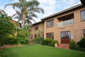 a brick building with a palm tree and a yard at Kairos Home Guesthouse in Middelburg
