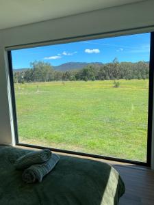 Un dormitorio con una gran ventana que da a un campo. en Grampians View Retreat, en Halls Gap