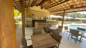 um pátio exterior com mesas e cadeiras e uma piscina em Guarajuba Oliveira em Camassari