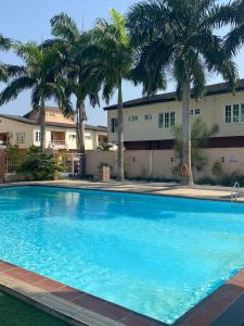 Una gran piscina con palmeras frente a un edificio. en QW5 APARTMENTS and SUITE, en Lekki