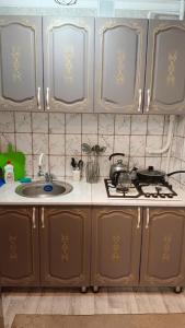 una cucina con lavello, piano cottura e armadietti di Квартира в Центре Шымкента Плаза a Shymkent