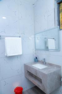 un bagno bianco con lavandino e specchio di Ruhondo Beach Resort a Ruhengeri Altre 77 foto