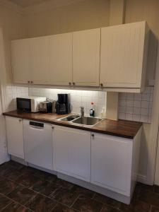 una cucina con mobili bianchi e un lavandino di 3 roms leilighet Narvik sentrum a Narvik