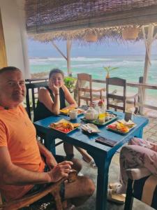 a man and woman sitting at a table with food at The Sea Sun villa in Unawatuna