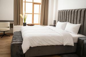 une chambre avec un grand lit blanc et une chaise dans l'établissement LIVELY Weiße Dame Gronau, à Gronau