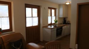 a kitchen with white cabinets and windows and a table at Scharbachhof in Glottertal