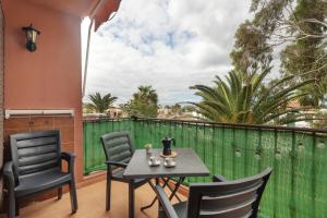 a patio with a table and chairs and a green fence at Feel The Sun In Tenerife in Costa Del Silencio