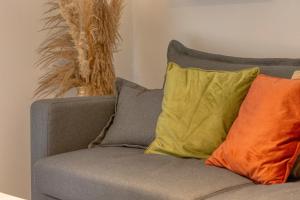 eine graue Couch mit zwei bunten Kissen darauf in der Unterkunft Le Nid Vouté charmant appartement avec terrasse situé au coeur de Rouen in Rouen