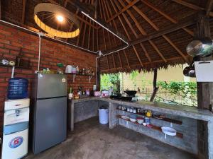 cocina con nevera y pared de ladrillo en Sanctuary Hostel - Art & Adventure, en Phra Ae beach