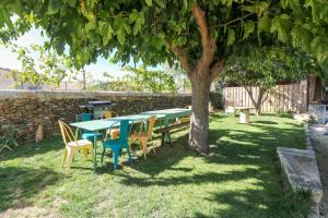 une table de pique-nique et des chaises assises sous un arbre dans l'établissement Authentic Country House with pool near Uzes, à Fontarèches