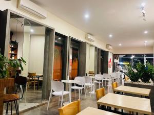 a restaurant with white chairs and tables and windows at Chhouy Vathna Angkor Boutique in Siem Reap