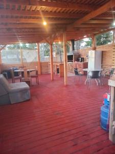 a screened in porch with a wooden floor and tables and chairs at Cabañas Tinaja y Sauna Laguna Verde Valparaiso in Valparaíso