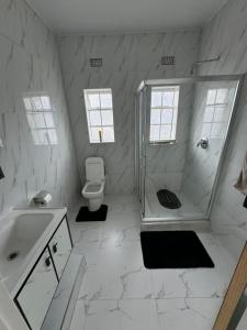 um banheiro branco com chuveiro e vaso sanitário em Yeta Apartments em Livingstone