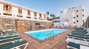 a swimming pool with lounge chairs and a building at Apartamentos Montecarlo in Puerto Rico de Gran Canaria