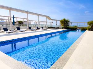 einen großen Pool mit Liegestühlen neben einem Gebäude in der Unterkunft Island Bliss 2 BR with Private Beach and Pool in Al Marjan Island in Ras al Khaimah