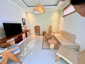 a living room with a flat screen tv and chairs at Villa Lulu - Uluwatu Nusa Dua in Ungasan