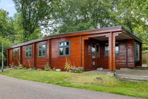 a small wooden cabin with trees in the background at Casa Rosa - Sfeervolle cottage met jacuzzi in Erm