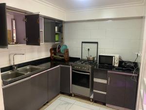 Una cocina con estufa, fregadero y microondas. en Chibuzor Apartment, en Lagos