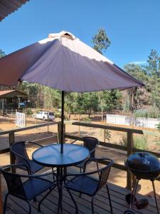 a table and chairs with an umbrella on a deck at Cabañas Tinaja y Sauna Laguna Verde Valparaiso in Valparaíso