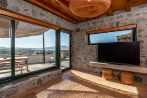 sala de estar con TV de pantalla plana y ventanas grandes. en Petra Residence Mini Pool Spa, en Adamas