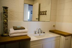 une salle de bain avec un lavabo et un miroir dans l'établissement Kywong Beach Cottage - cosy beach escape, à Bawley Point