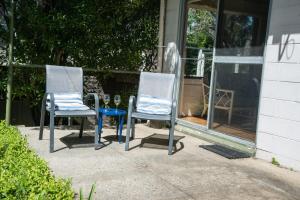 Deux chaises et un verre à vin assis sur une terrasse dans l'établissement Kywong Beach Cottage - cosy beach escape, à Bawley Point
