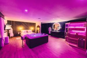 DoigniesLe Domaine de Louverval Suite & Spa的一间卧室设有紫色的房间,配有一张床和一个浴缸