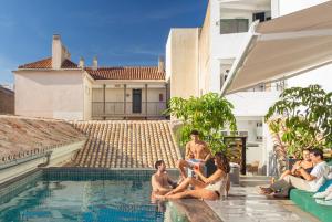 a group of people sitting around a swimming pool at Coeo Hernan Ruiz Rooftop Pool Hostel in Málaga