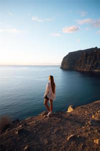 Eine Frau, die auf einer Klippe mit Blick auf den Ozean steht. in der Unterkunft Radisson Resort & Residences Tenerife - Adults Only in Puerto de la Cruz