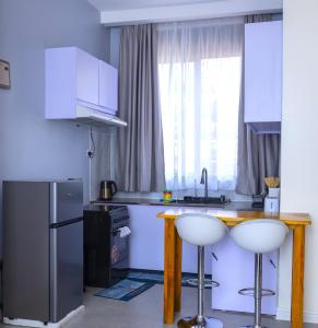 a kitchen with a table and two white stools at Serene 1bed, 1bath studio Apartment in Mbarara