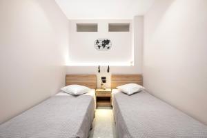 deux lits dans une chambre aux murs blancs dans l'établissement The Saltwater Suite 1 minute Beach, à Kos 29 autres photos