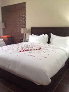 un grand lit avec des pétales de roses rouges dessus dans l'établissement Yatu International Hotel, à Dirē Kʼalu
