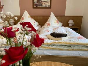 a bed with a dog laying on it with red flowers at Hotel-Pension Flechsig in Hartmannsdorf bei Kirchberg.