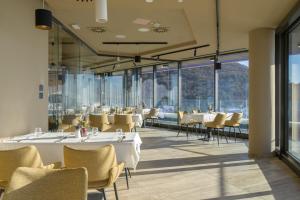 uma sala de jantar com mesas, cadeiras e janelas em Hotel Princeps em Sátoraljaújhely