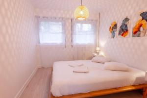 a bedroom with a bed with white sheets and a window at Le Bleu des Remparts in Chalon-sur-Saône