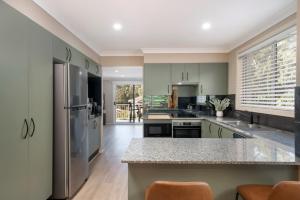 a kitchen with green cabinets and stainless steel appliances at Luxury at Lagoon Estate in Nelson Bay