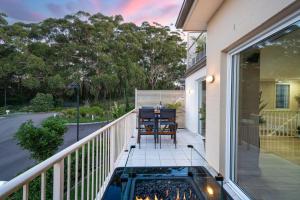 a patio with a hot tub and a table on a balcony at Luxury at Lagoon Estate in Nelson Bay