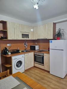 a kitchen with a white refrigerator and a dishwasher at Апартамент Радост in Bansko