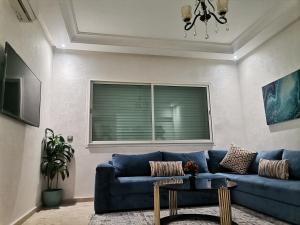 Una sala de estar con un sofá azul y una ventana. en Central Park, en Mohammedia