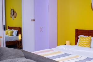 a bedroom with two beds and a yellow wall at Serene 1bed, 1bath studio Apartment in Mbarara
