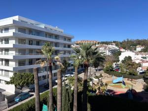 a large white building with palm trees and a park at The White Pearl Marbella in Marbella