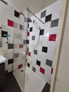 a bathroom with a shower with red and white tiles at Logis Hotel Les Gravades Ussel in Ussel
