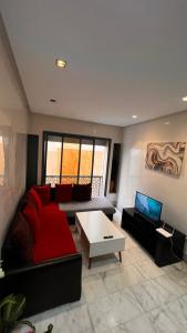 a living room with a red couch and a table at Beautiful appartement with pool view in Mohammedia +1 photo