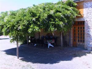 a table and chairs under a tree in front of a building at La Plaine in Vaissac