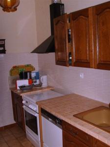 a kitchen with wooden cabinets and a white stove top oven at La Plaine in Puygaillard-de-Quercy