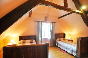 - une chambre mansardée avec 2 lits et une fenêtre dans l'établissement Gîte du hameau de Labat, à Beauregard