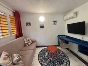 a living room with a couch and a table at Tika Bungalow - Pisicne, Wifi, Grande Terrasse privée et Accès Plage à pied in Grand-Bourg