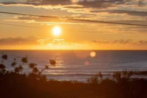 a sunset over the ocean with the sun in the sky at The Beach House Bawley Point - near Bawley Beach in Bawley Point